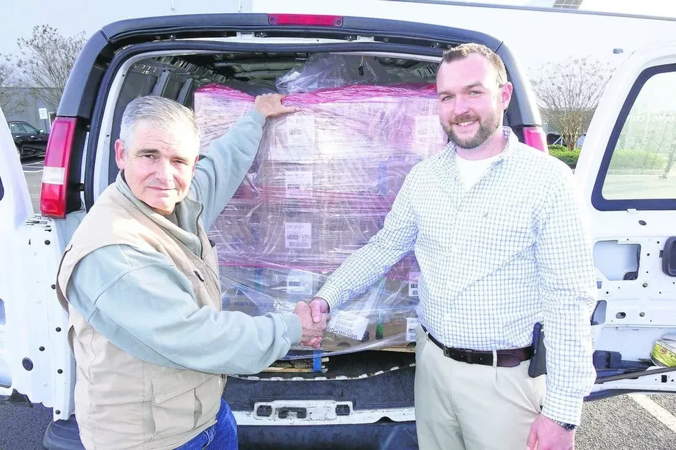 Community Storehouse staff shaking hands with a food donor in front of a loaded van